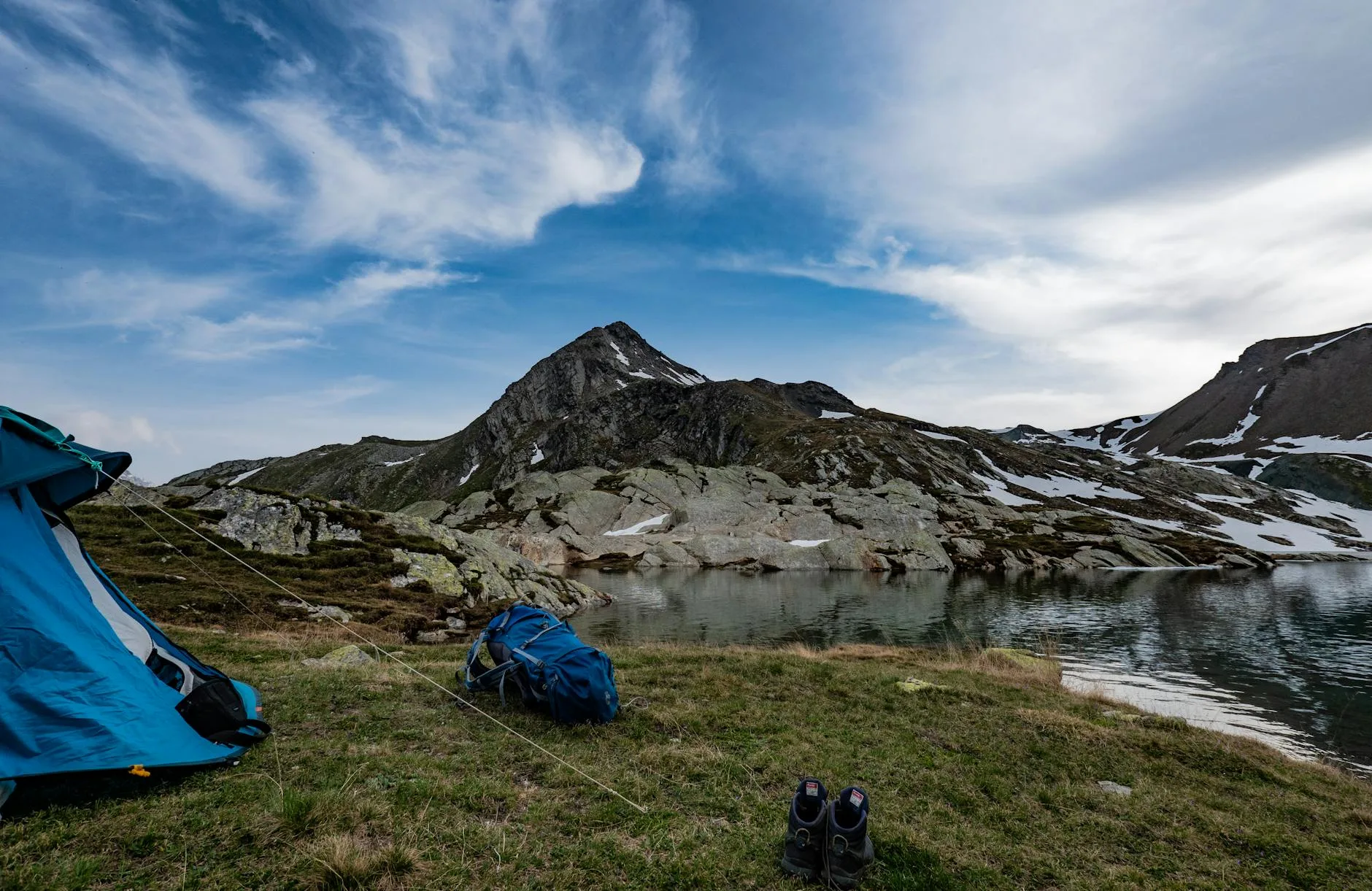 Man sitting by tent in a forested wild campsite