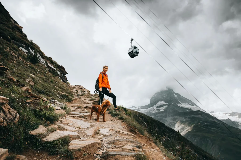 Hiker in a waterproof jacket walking on a mountain trail