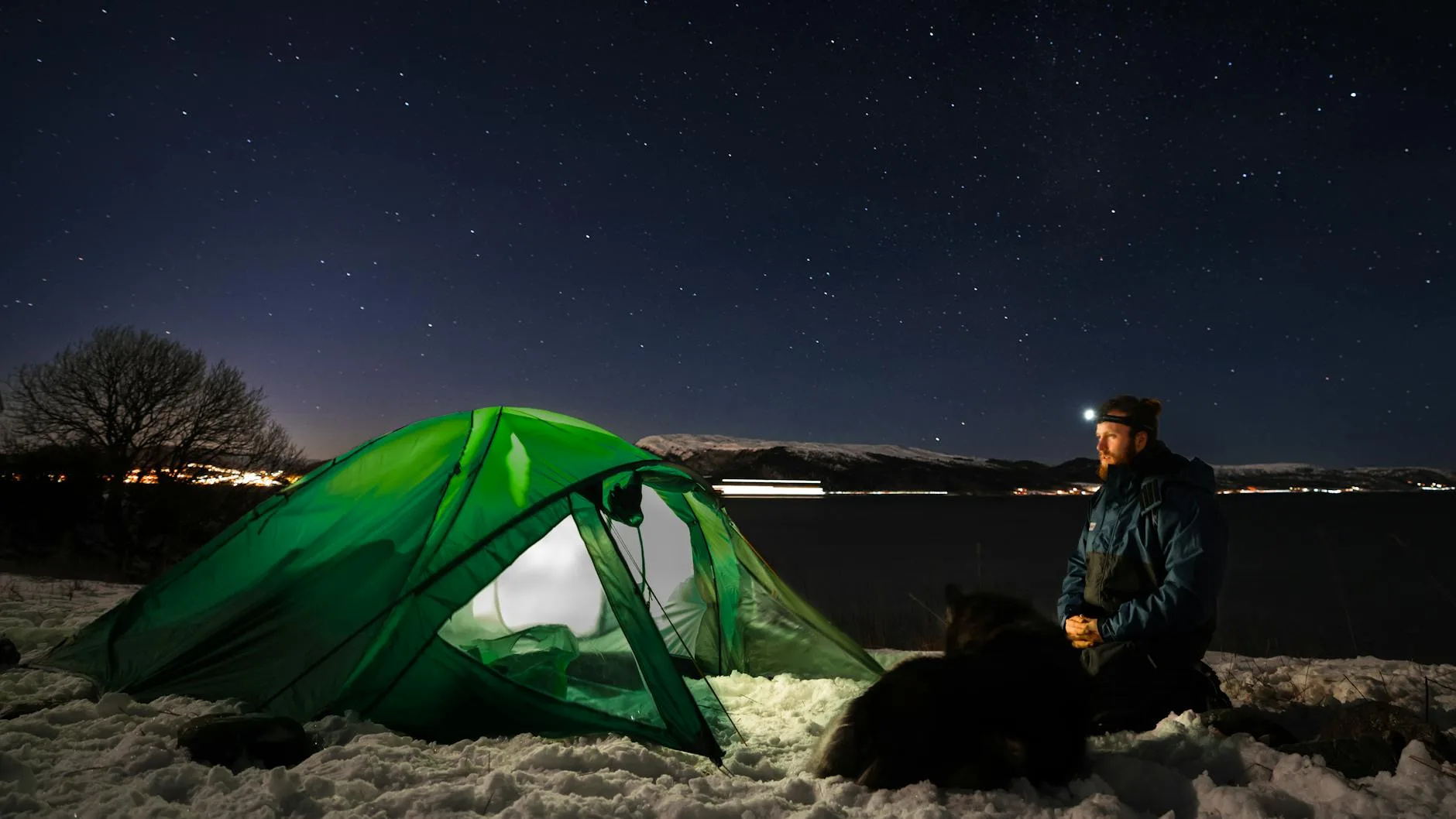 Camper using a head torch to read a map inside a tent at night