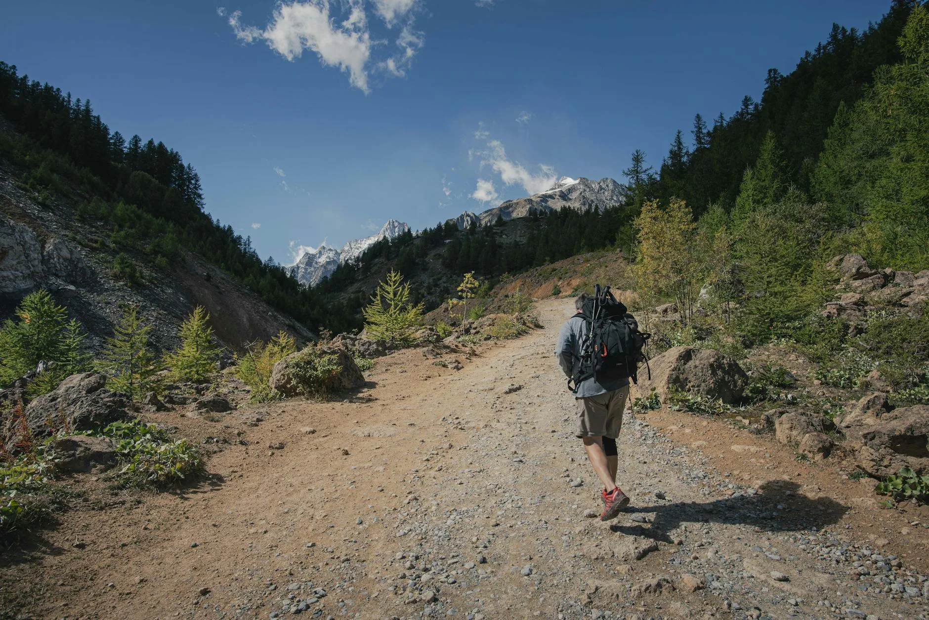 Hiker trekking along a mountain trail with a loaded backpack