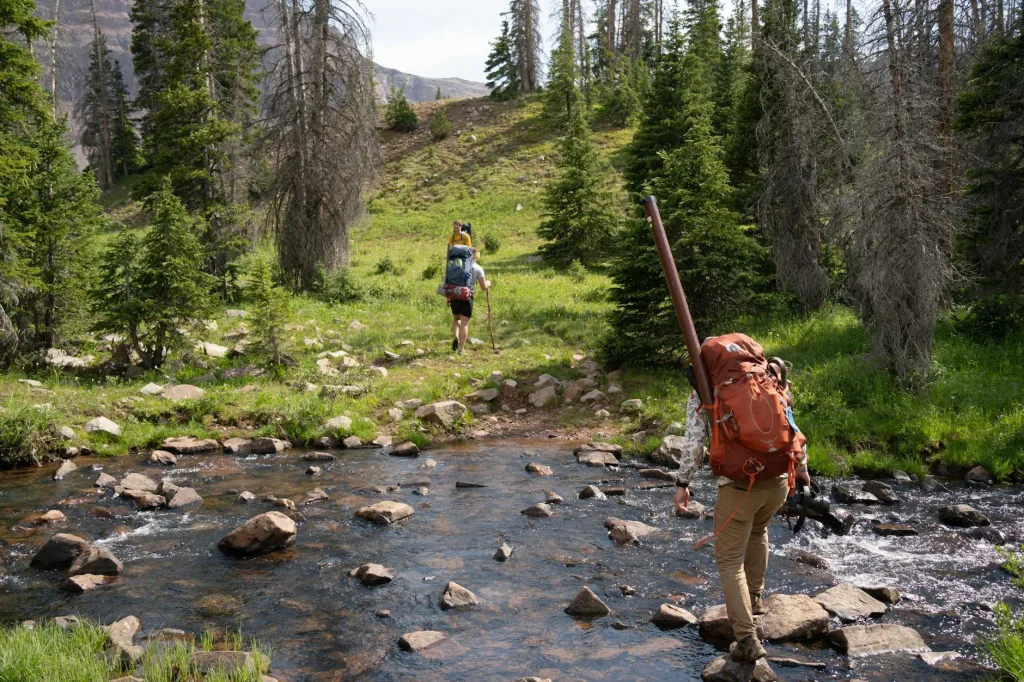 Hiker by a mountain stream collecting water