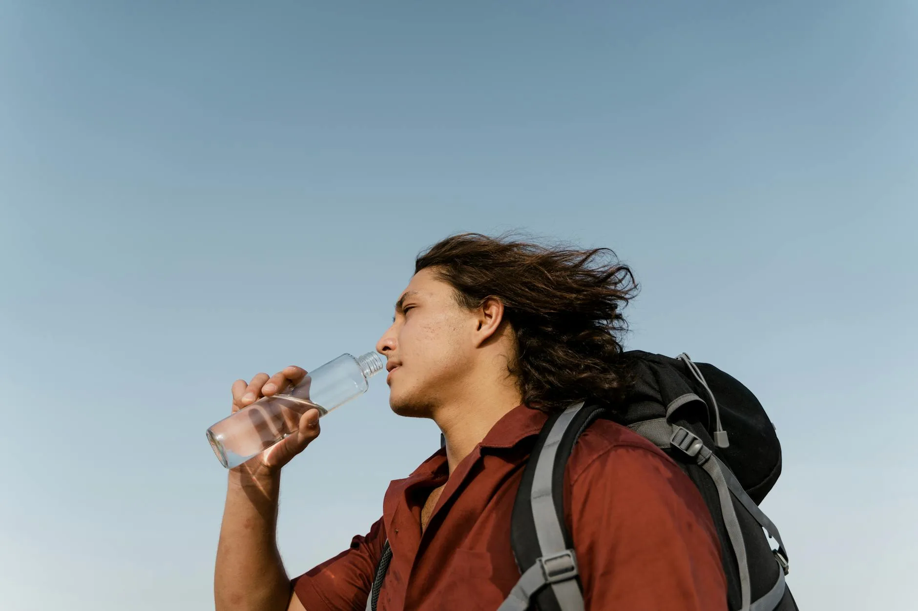 Hiker using a water filter bottle on a trail