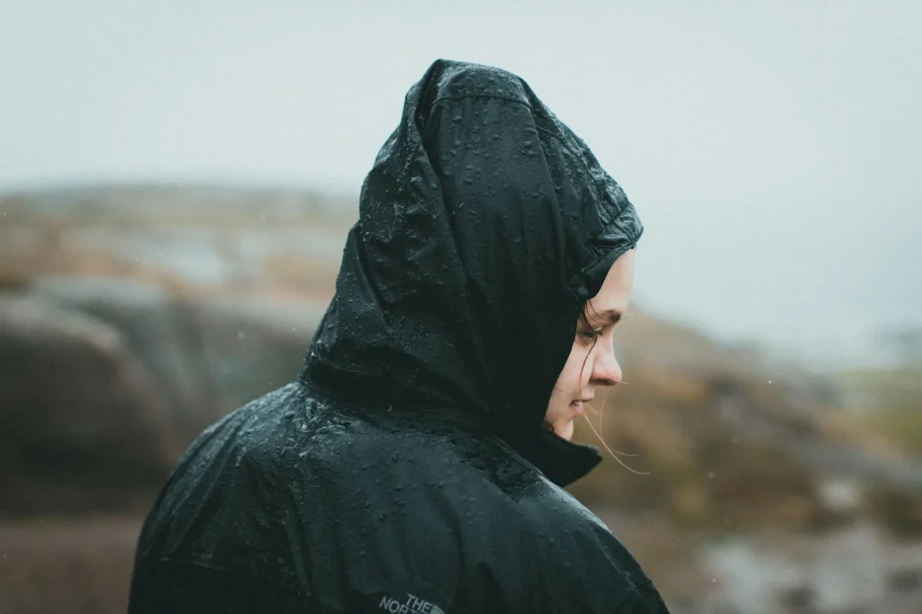 Hiker wearing a waterproof jacket walking in the rain outdoors