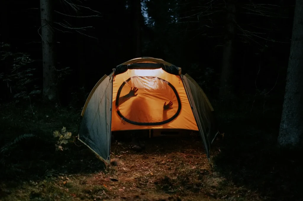 Camping lantern glowing warmly inside a tent at night