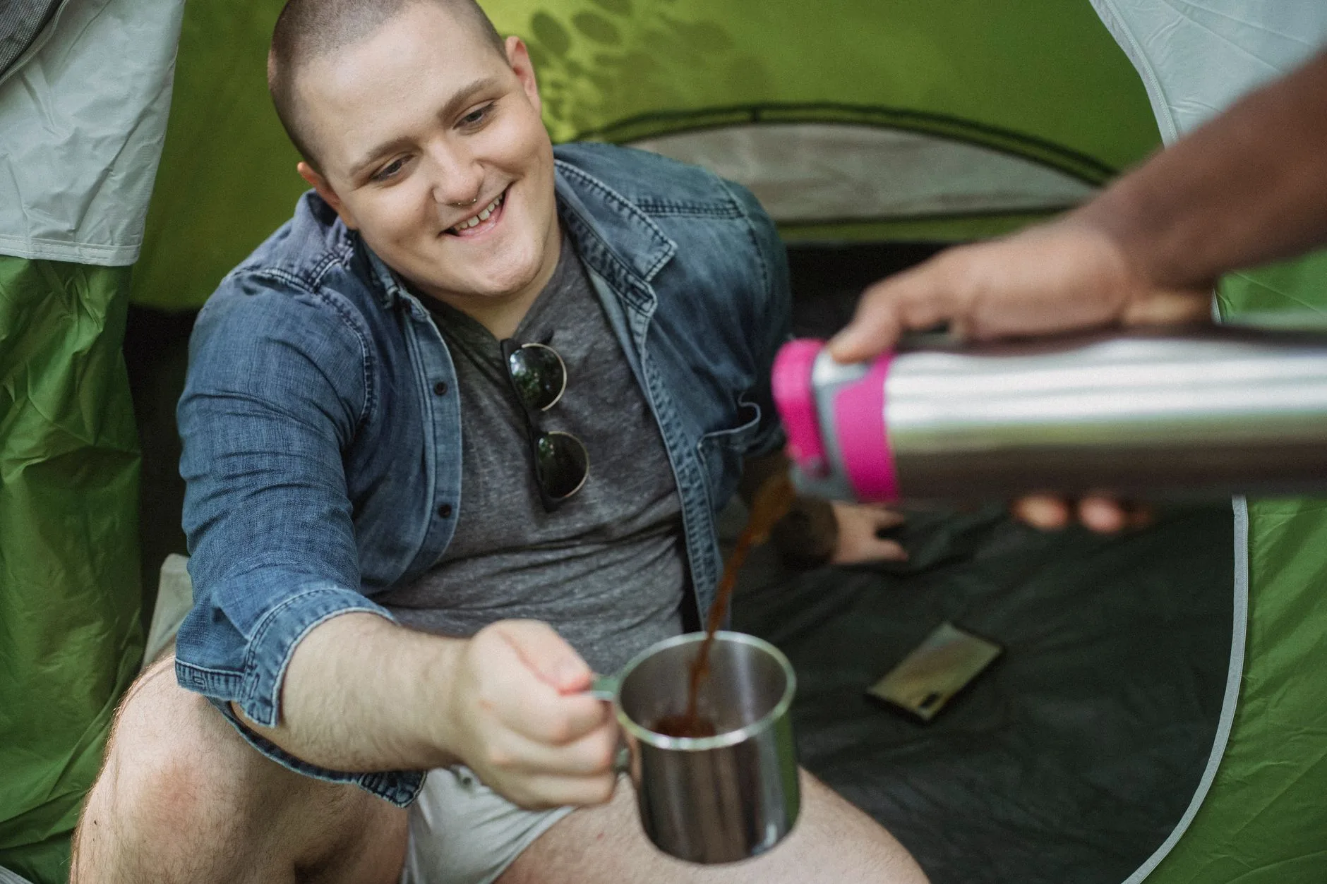 Coffee being poured into a camping mug inside a tent